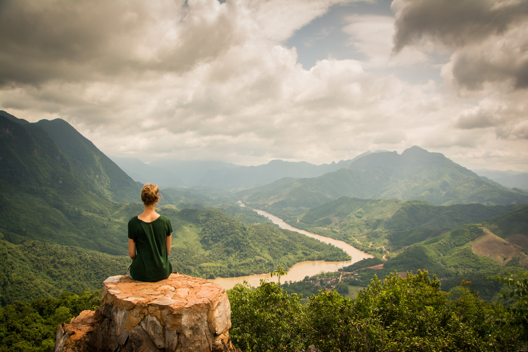 A woman sits on a rock